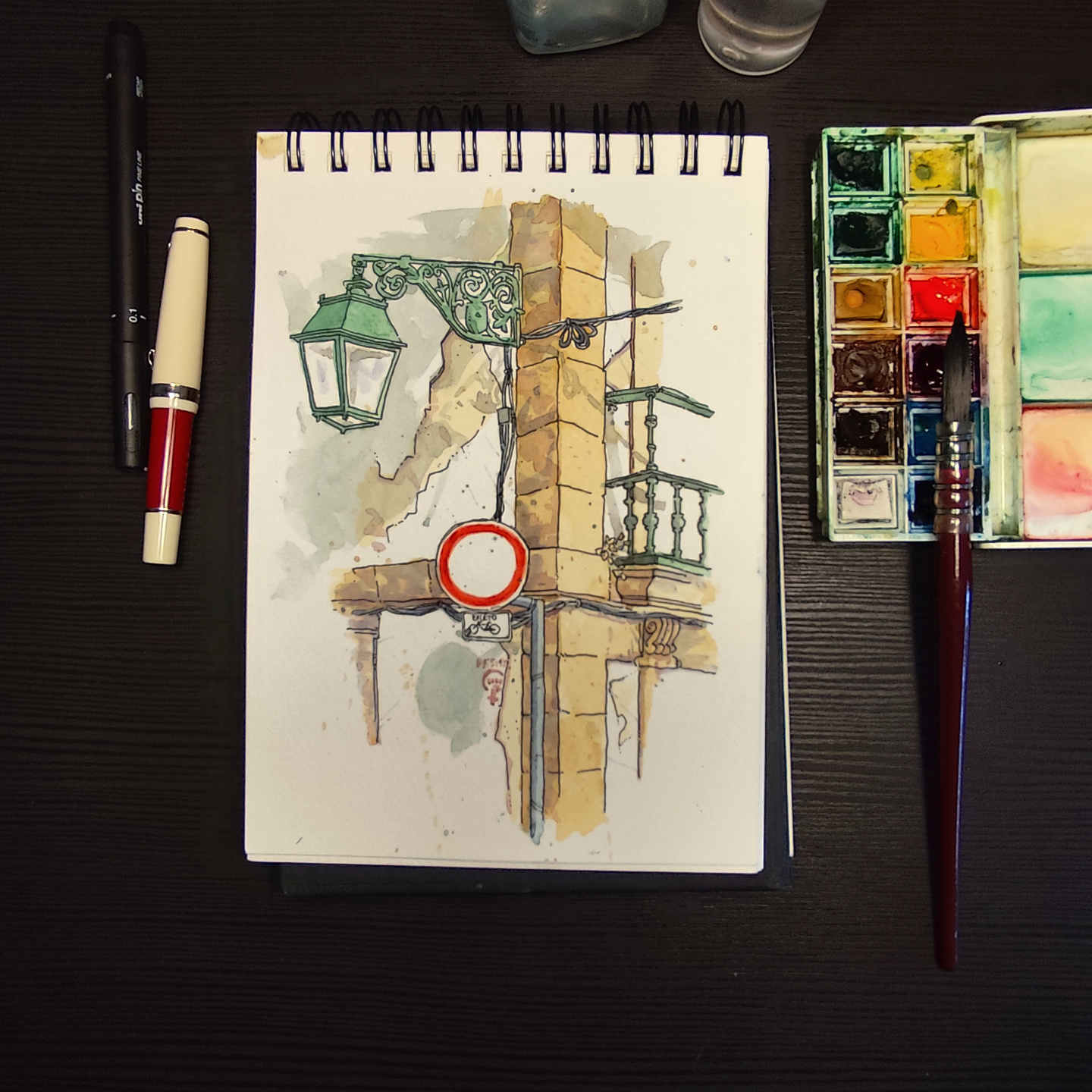 watercolor of a corner in Viana do Castelo, with an iron street lamp and a round traffic sign